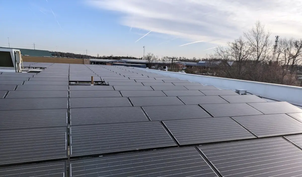 Řady fotovoltaických panelů na ploché střeše firemní haly